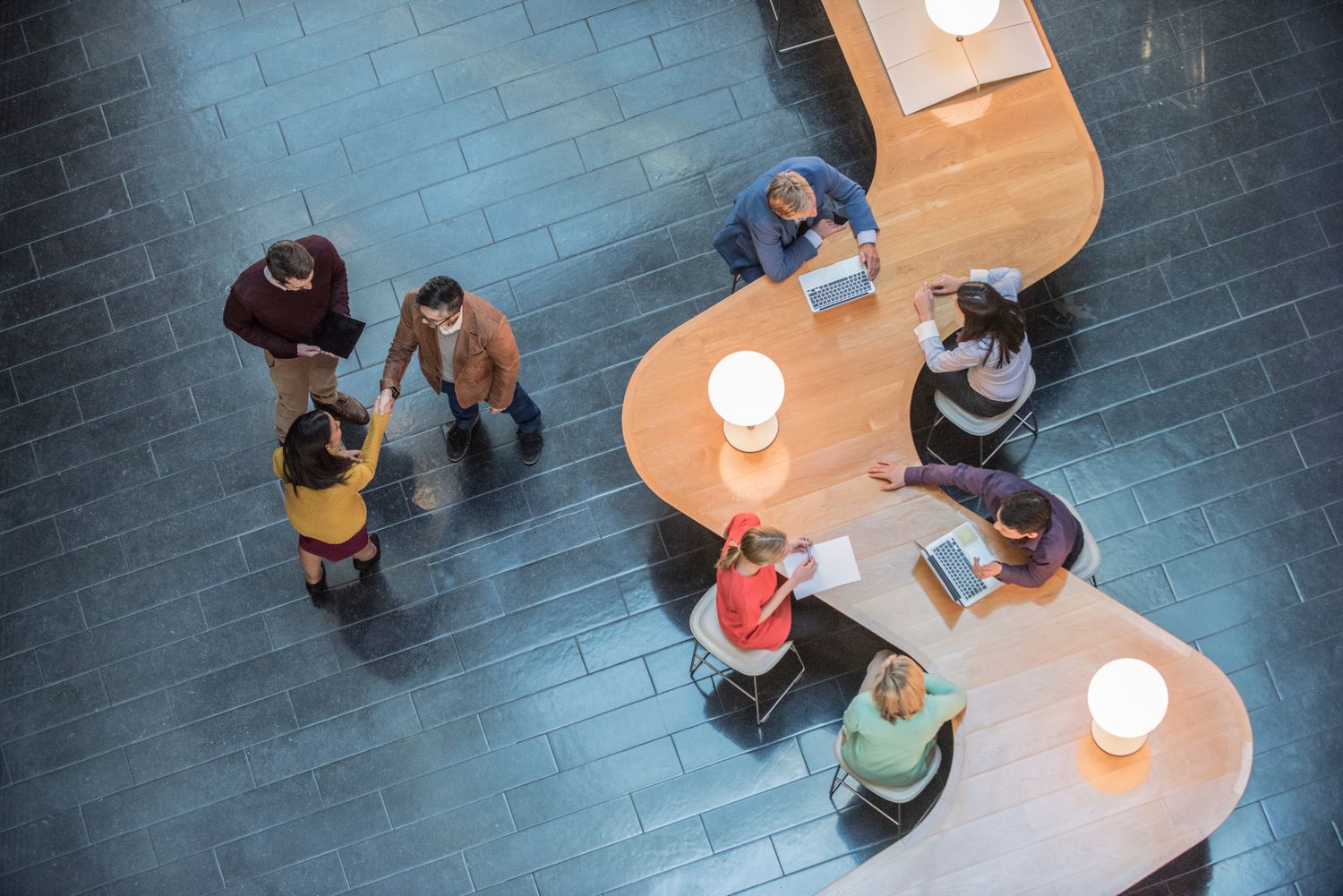an aerial view of a group of employees gathered around a long, S-shaped table